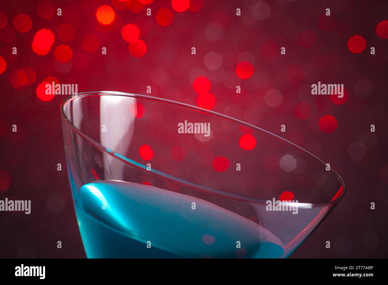 Detail eines glasblauen Cocktails auf rotem, hellem Bokeh-Hintergrund Stockfoto