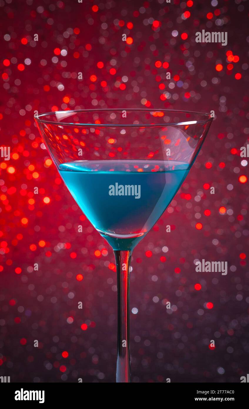 Ein Glas blauer Cocktail auf rotem, hellem Bokeh-Hintergrund Stockfoto
