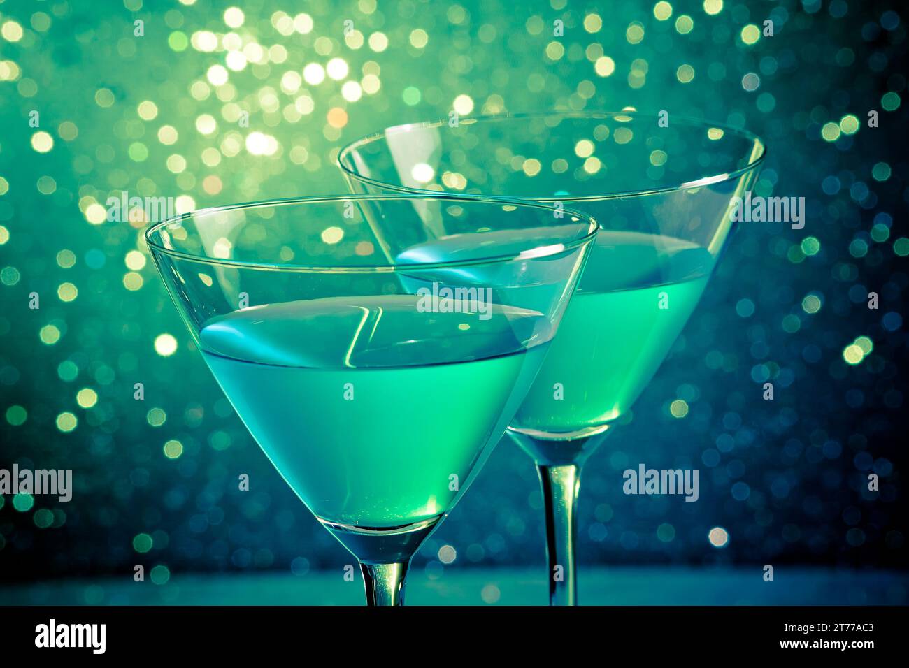 Gläser blauer Cocktail auf dunkelgrünem Hintergrund mit hellem Bokeh auf dem Tisch Stockfoto