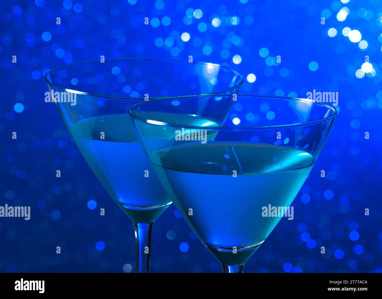 Detail eines Brillenglases blauer Cocktail auf blauem, heller Bokeh-Hintergrund Stockfoto