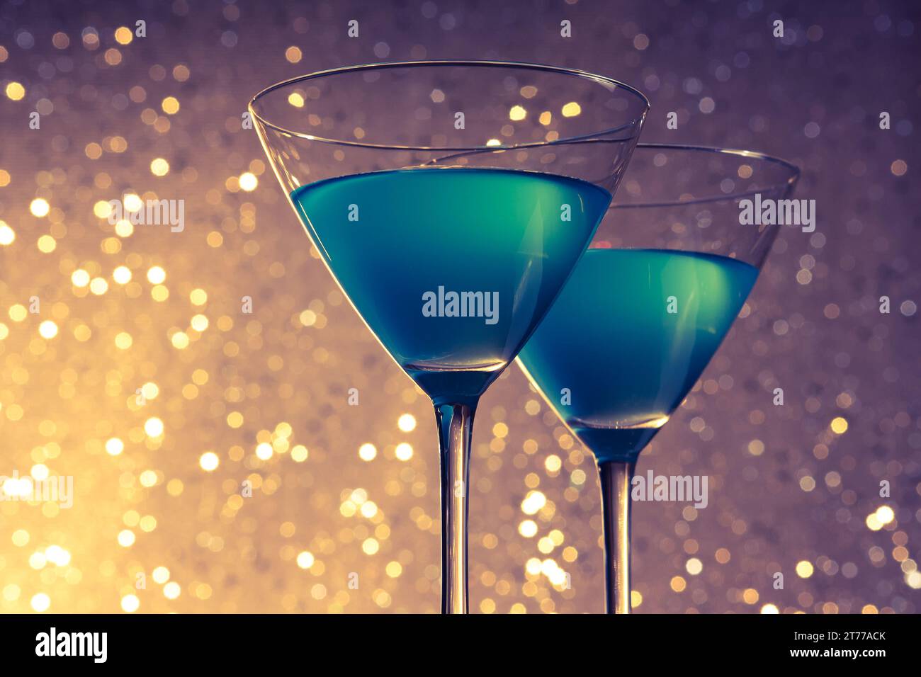 Gläser blauer Cocktail auf goldenem und violettem heller Bokeh-Hintergrund auf dem Tisch Stockfoto