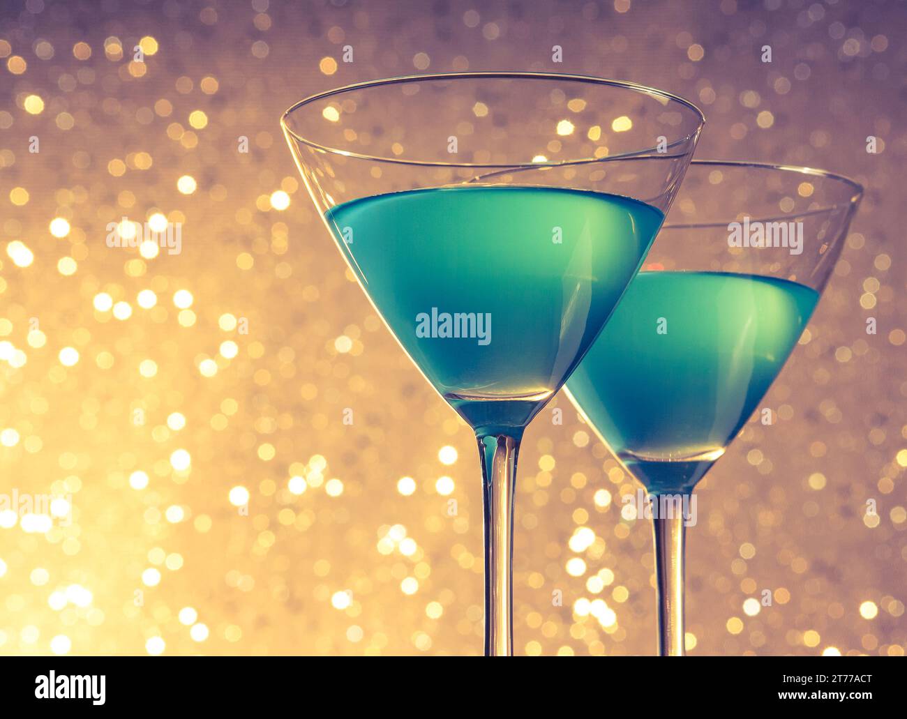 Gläser blauer Cocktail auf goldenem und violettem heller Bokeh-Hintergrund auf dem Tisch Stockfoto