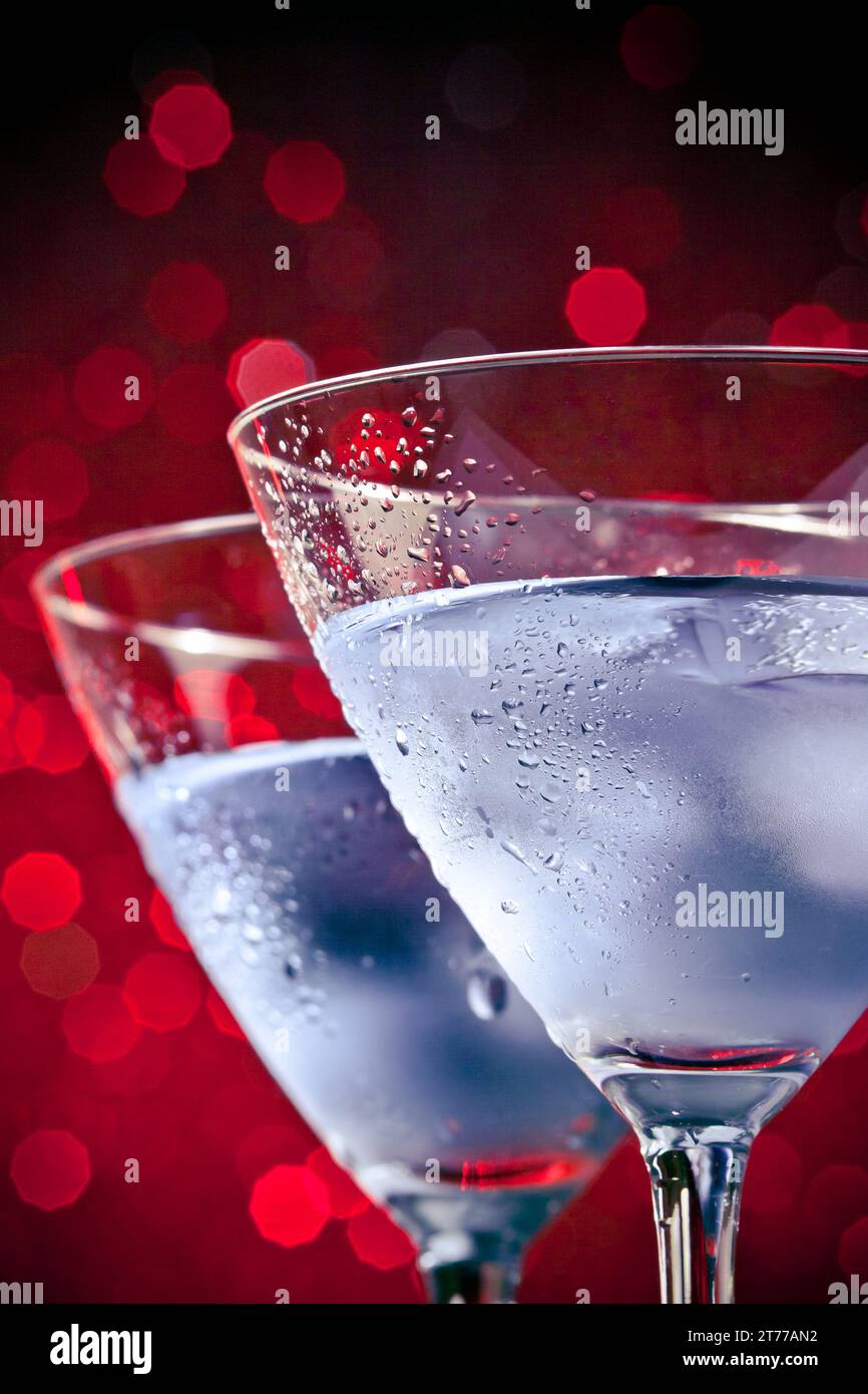 Detail der Gläser des frischen Cocktails mit Eis auf rotem hellem Bokeh-Hintergrund mit Platz für Text Stockfoto