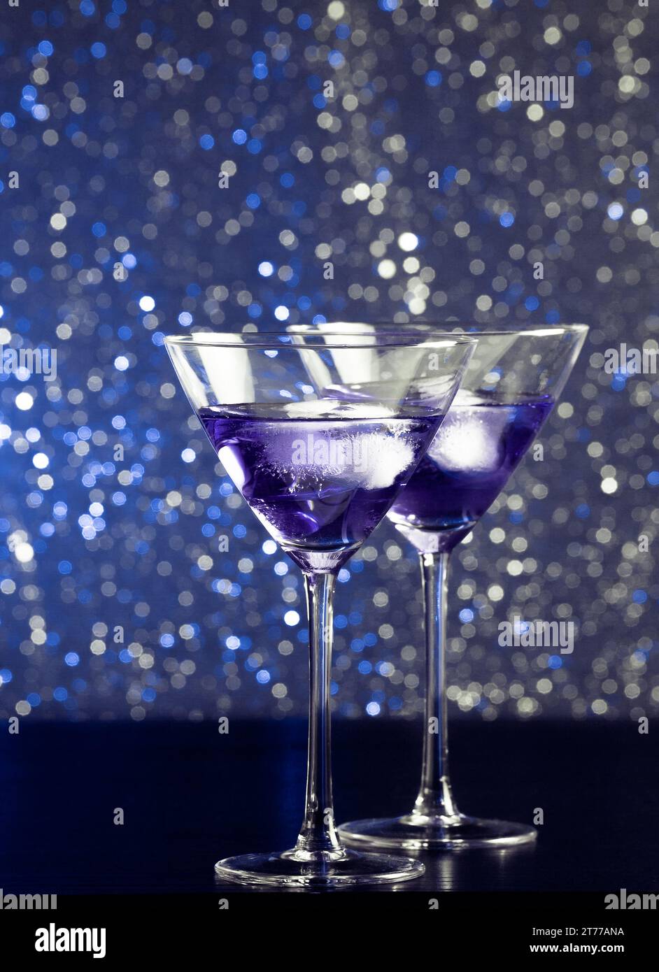 Gläser mit frischem Cocktail mit Eis auf blauem hellem Bokeh-Hintergrund auf Bartisch Stockfoto