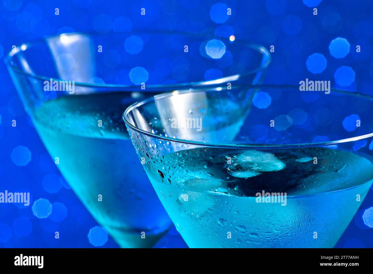 Ein paar Gläser frischer blauer Cocktail mit Eis auf blauem hellem Bokeh-Hintergrund Stockfoto