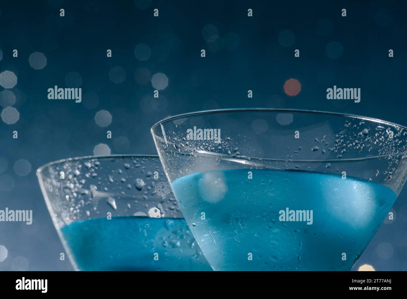 Detail der Gläser des frischen blauen Cocktails mit Eis auf blauem hellem Bokeh-Hintergrund Stockfoto
