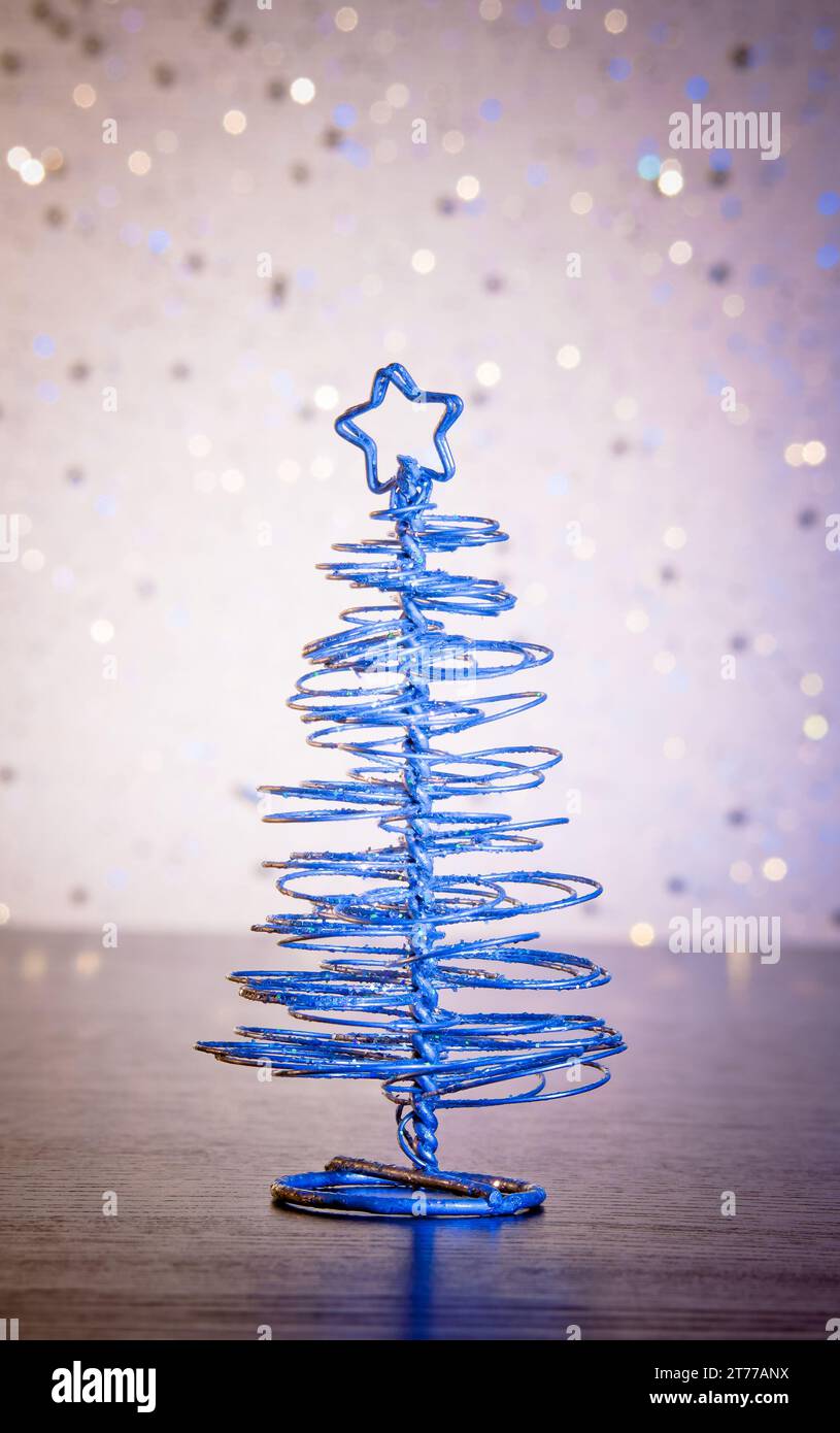 Moderner weihnachtsbaum in blauem Metallic auf Holztisch auf hellem Bokeh-Hintergrund Stockfoto