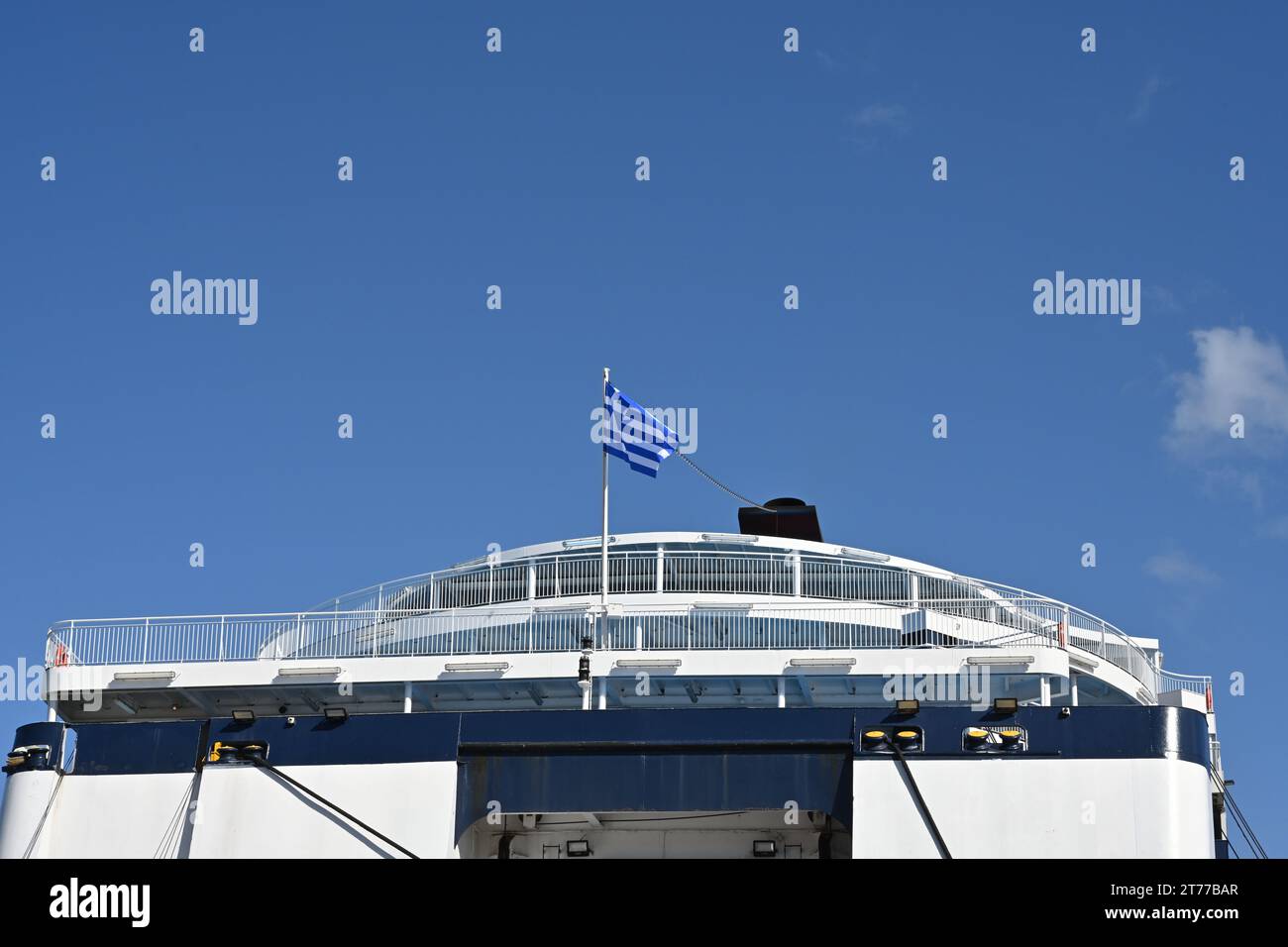 Achter Teil der Passagierfähre mit blauem und weißem Rumpf und griechischer Flagge oben wird vor klarem Himmel beobachtet. Stockfoto