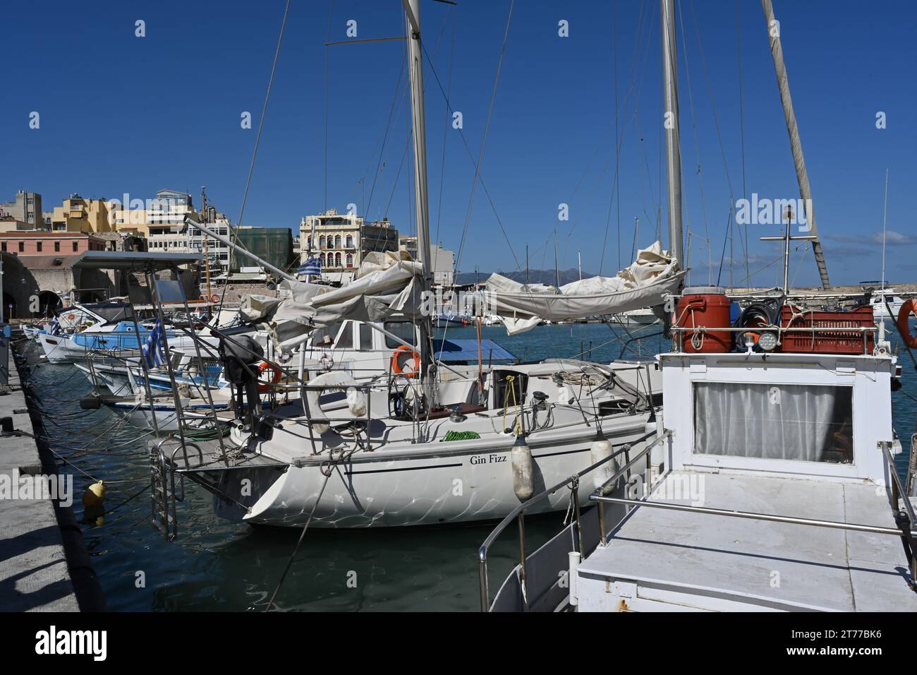Segelboote und Yachten mit weißen Rümpfen im griechischen Hafen von Heraklion in der Nähe des Stadtzentrums im Sommer. Stockfoto