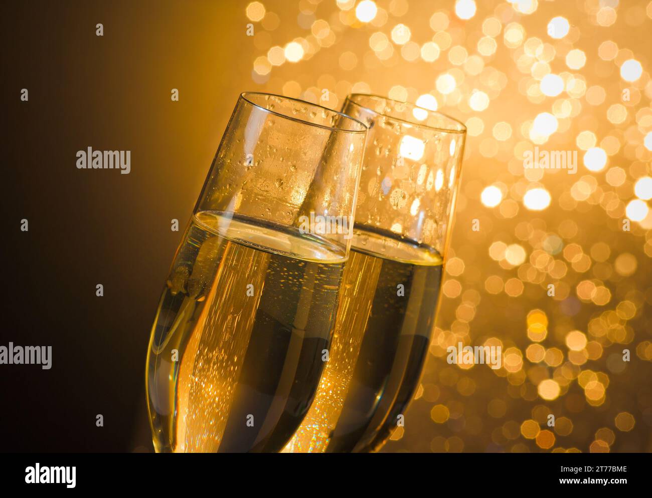 Detail der Sektflöten mit goldenen Blasen auf dunklem goldenem heller Bokeh-Hintergrund mit Platz für Text Stockfoto