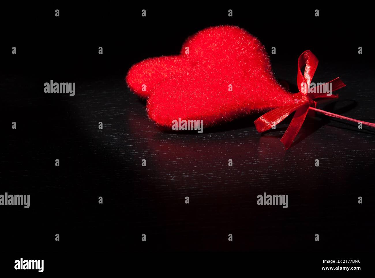 Zwei dekorative samtrote Herzen auf schwarzem Dunkellicht und auf Holztisch mit Platz für Text, Konzept des valentinstag Stockfoto
