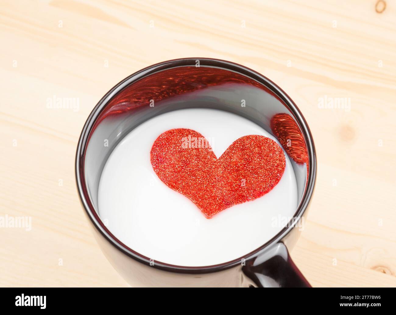 Tasse Milch mit dekorativem Herz auf Holztisch mit Platz für Text, Konzept des valentinstag Stockfoto
