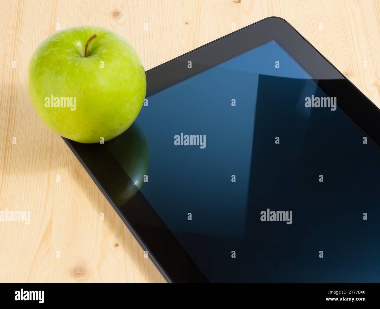 Digitaler Tablet-pc und grüner Apfel auf Holztisch, Konzept zum Erlernen neuer Technologien Stockfoto