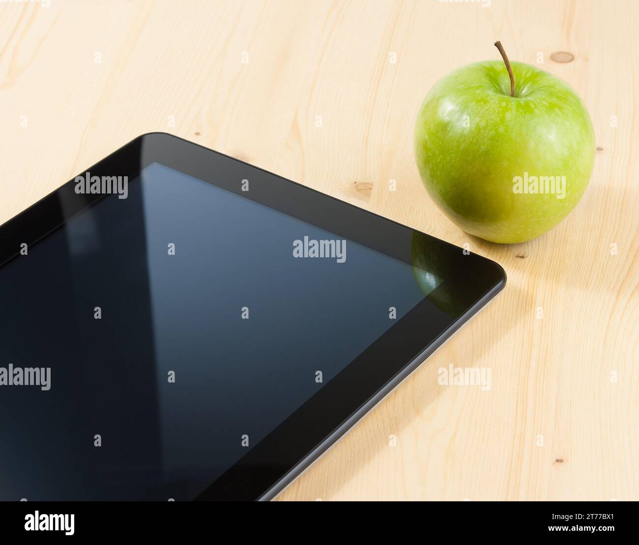 Intelligenter digitaler Tablet-pc und grüner Apfel auf Holztisch, Konzept zum Erlernen neuer Technologien Stockfoto