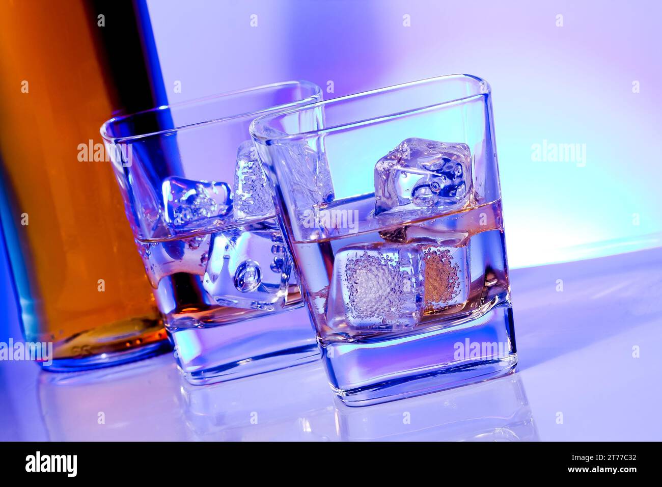 Ein paar Gläser alkoholischer Getränke mit Eis auf Disco blauem Licht auf weißem Tisch Stockfoto