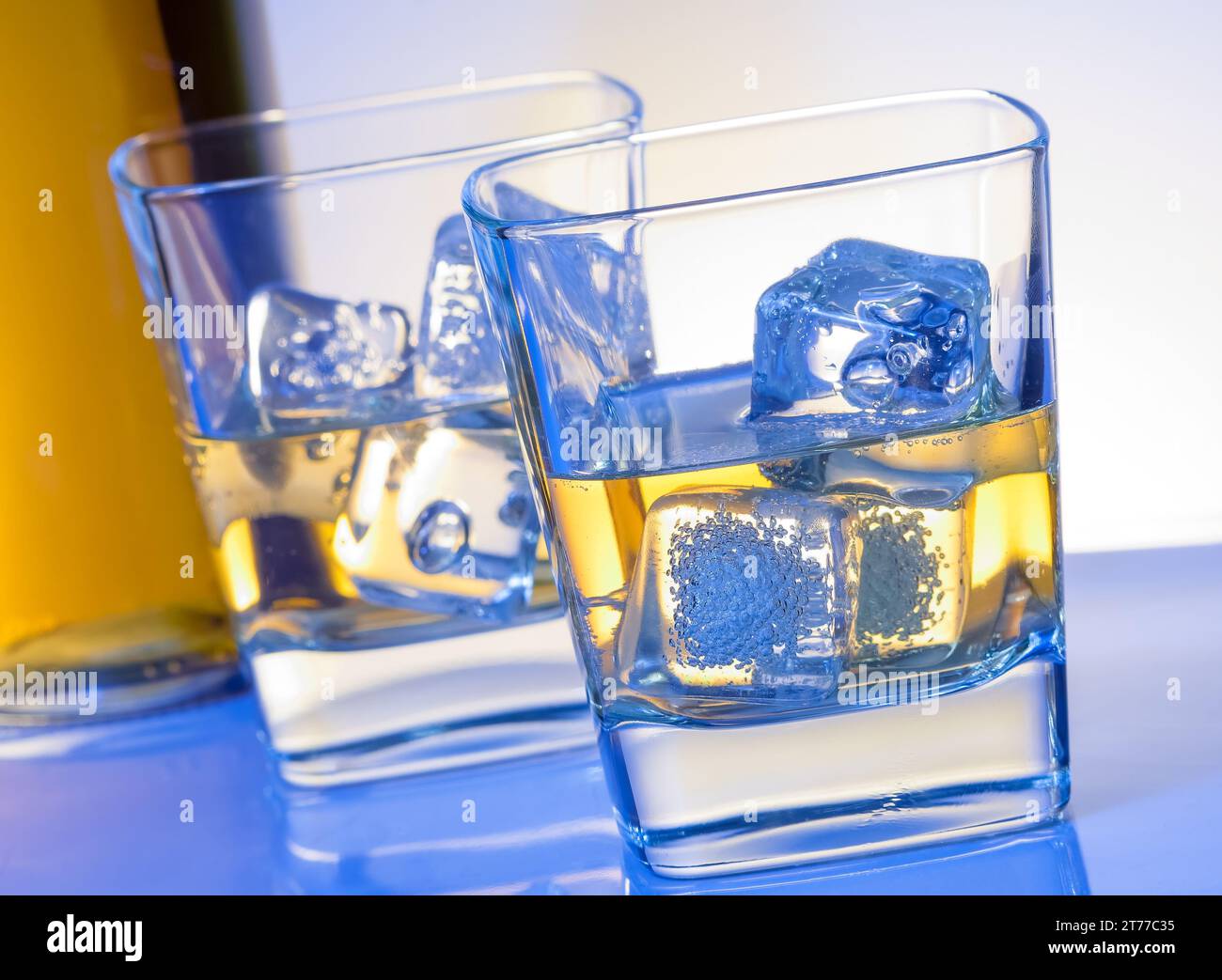 Zwei Gläser Whiskey mit Eis auf blauem Licht auf weißem Bartisch Stockfoto