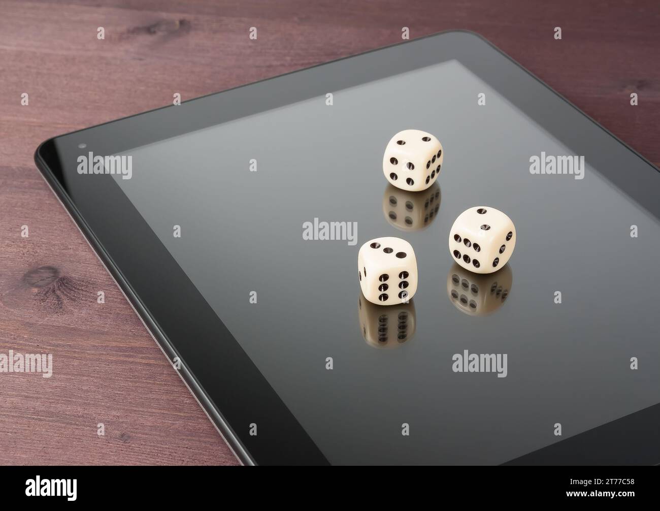 würfel auf einem digitalen Tablet-pc auf einem alten Holztisch, Konzept des texas-Spiels online Stockfoto