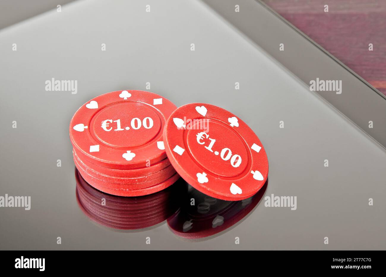 Glücksspielchips auf einem digitalen Tablet-pc auf einem alten Holztisch, Konzept des texas-Spiels online Stockfoto