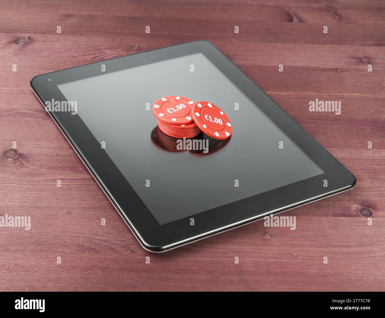 Rote Glücksspielchips auf einem digitalen Tablet-pc auf einem alten Holztisch, Konzept des texas-Spiels online Stockfoto