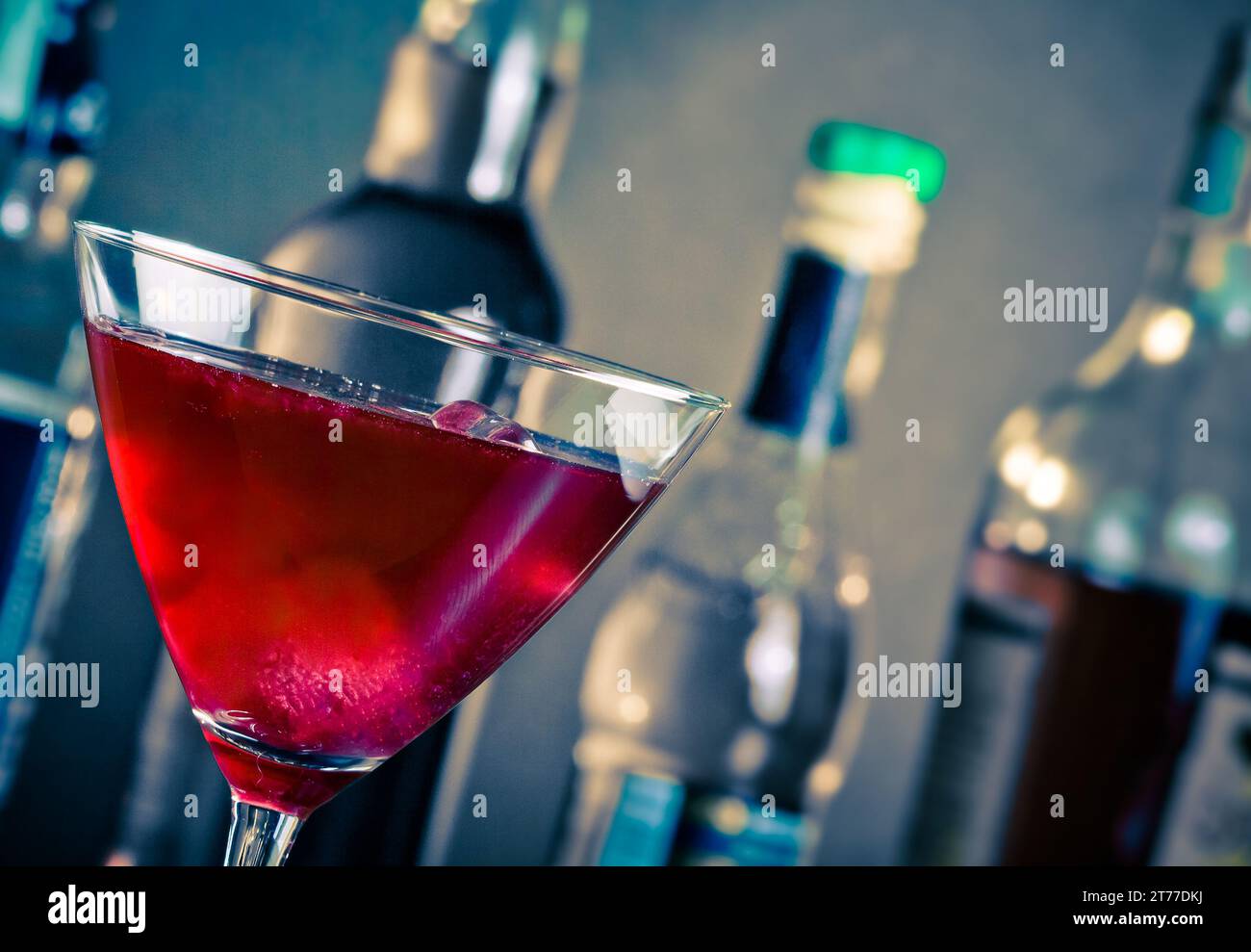 Roter Cocktail in ein Glas mit Eis auf blauem Licht Disco Atmosphäre Stockfoto