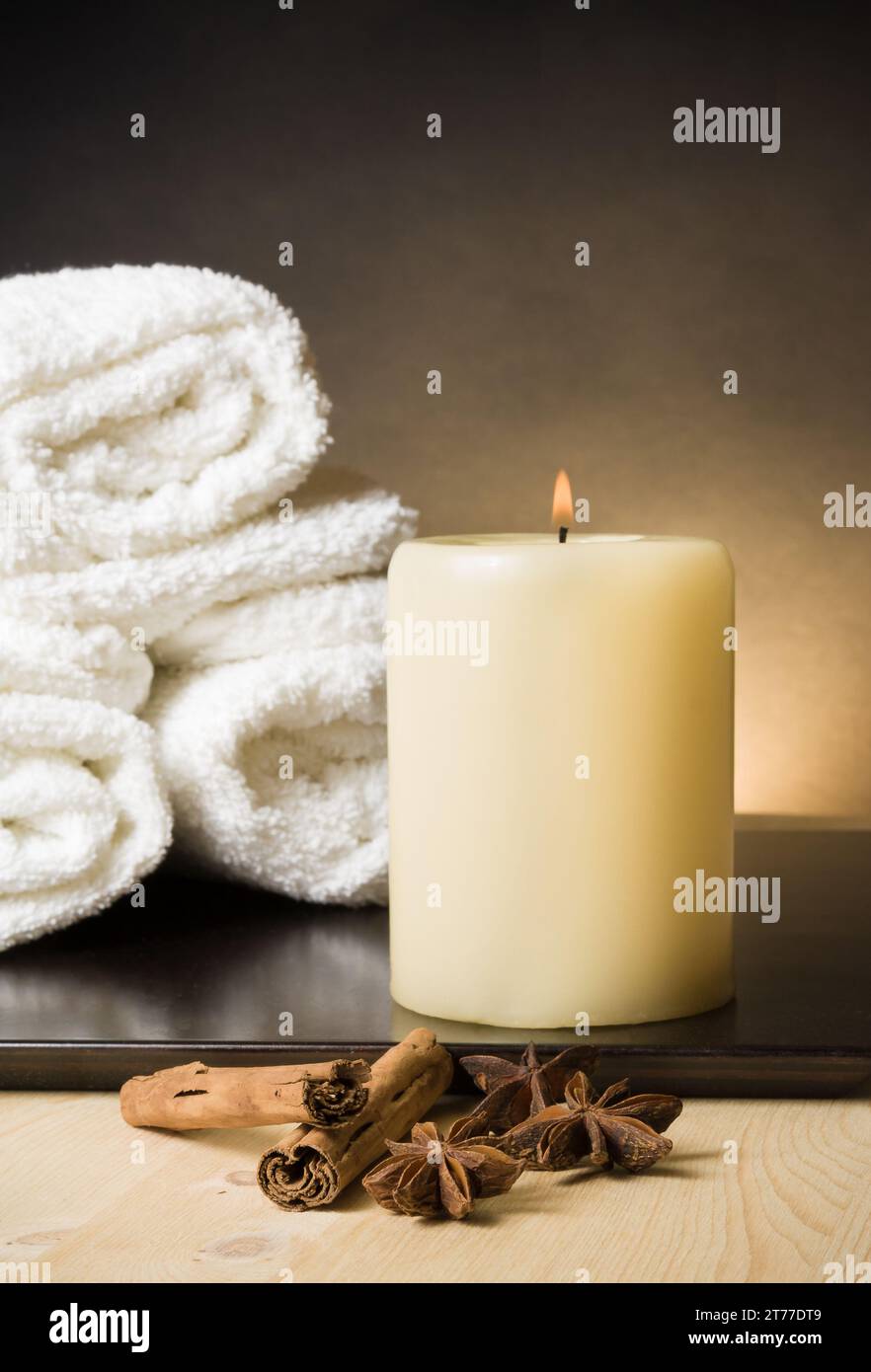 Spa-Massage-Hintergrund mit Handtuch und Kerze mit Gewürzen und Zimtgeschmack, warme Atmosphäre Stockfoto