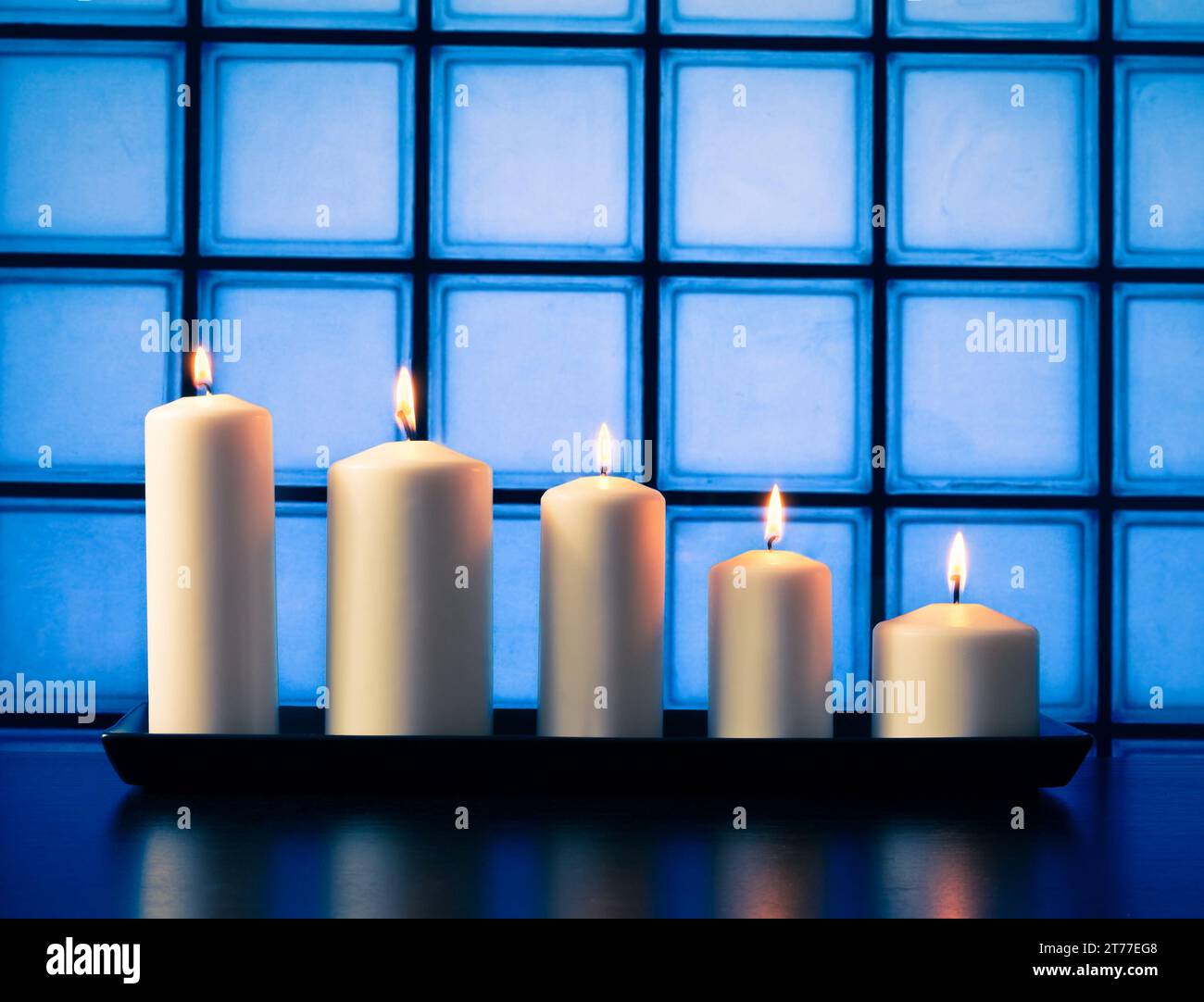Weiße Kerzen auf Holztisch auf blauem Hintergrund Stockfoto
