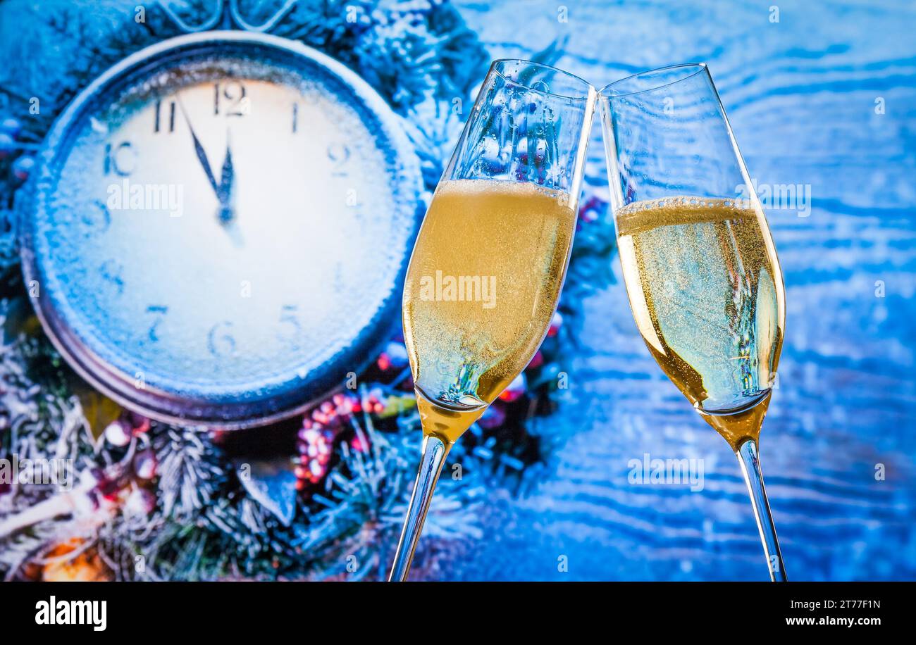 Silvester oder Weihnachten um Mitternacht mit Sektflöten mit goldenen Luftblasen lassen auf blauem Licht und Uhrhintergrund jubeln Stockfoto