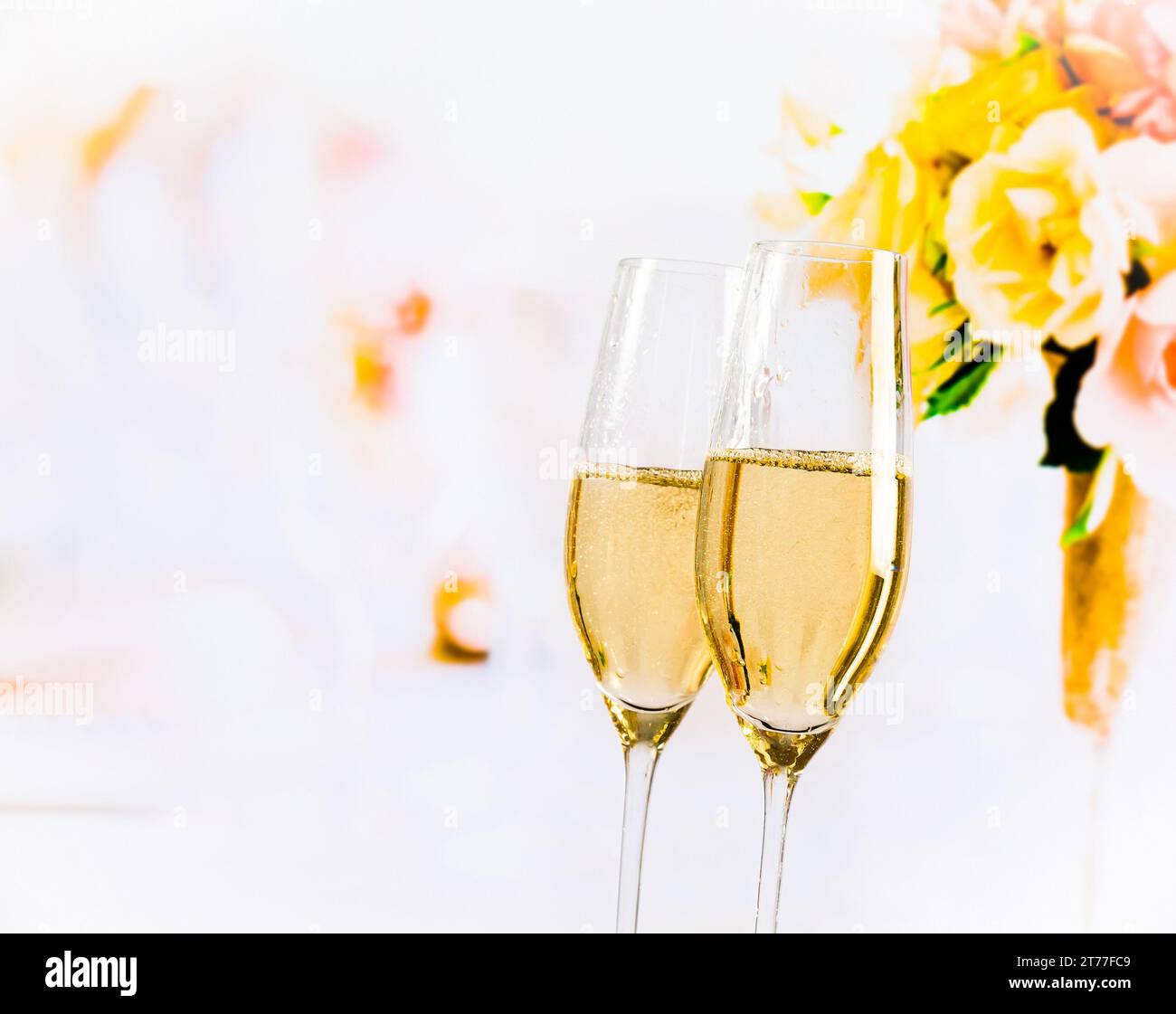 Champagnerflöten mit goldenen Blasen auf Hochzeitsblumen Hintergrund mit Platz für Text Stockfoto
