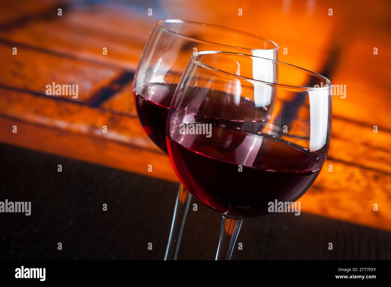 Zwei Rotweingläser auf Holztisch mit warmem Hintergrund, festliches und unterhaltsames Konzept Stockfoto