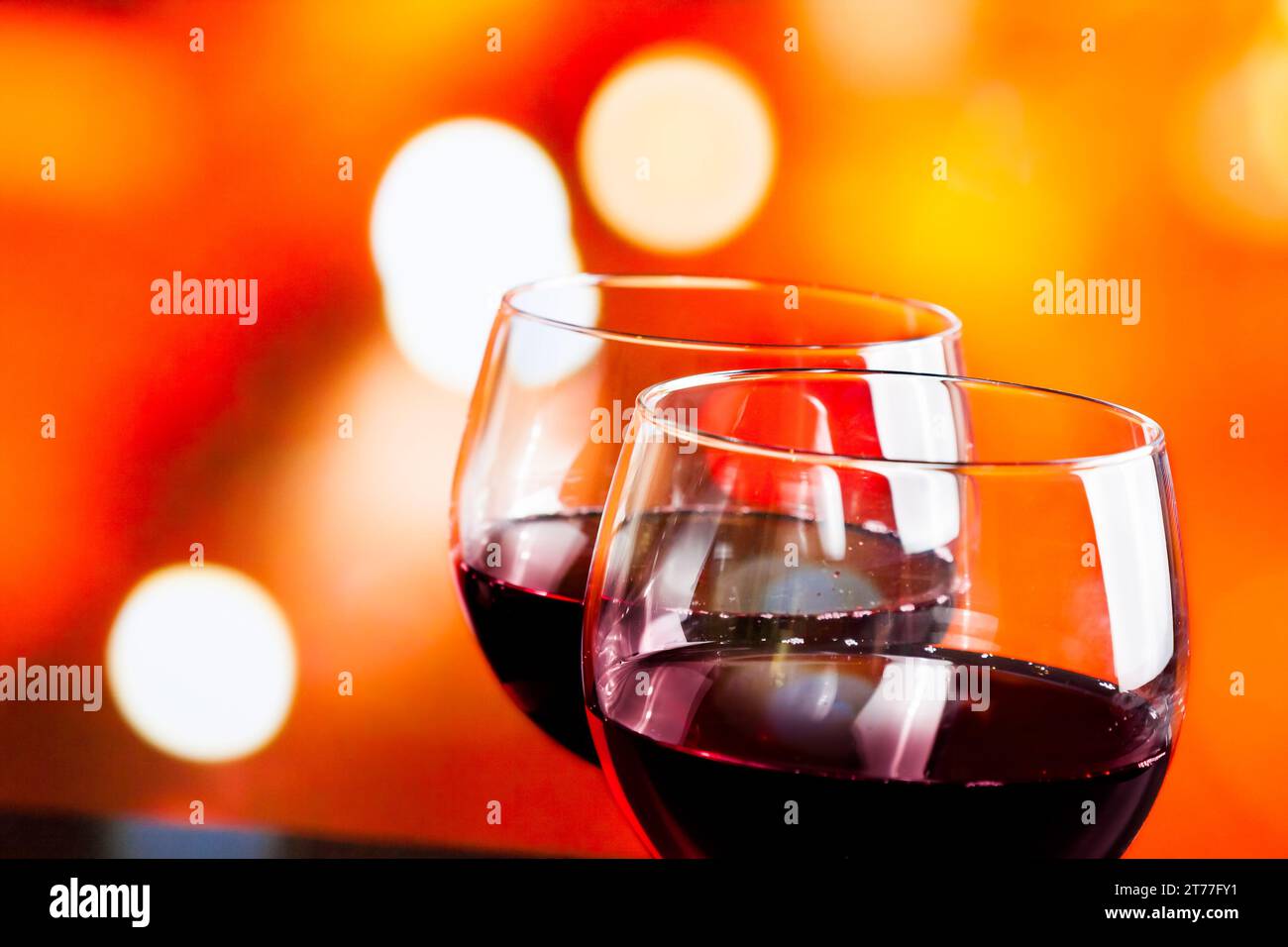 Rotweingläser vor farbenfrohen, unscharfen Lichtern im Hintergrund, festliches und unterhaltsames Konzept Stockfoto
