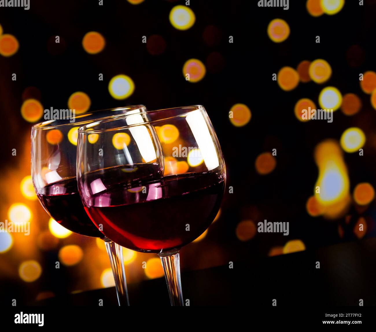 Zwei Rotweingläser auf Holztisch vor Bokeh-Lichtern, festliches und lustiges Konzept Stockfoto