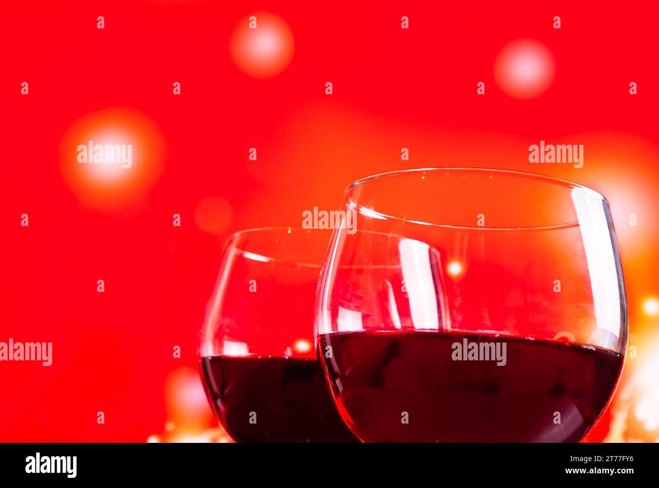 Zwei Rotweingläser neben der Flasche vor rotem Hintergrund, festliches und unterhaltsames Konzept Stockfoto