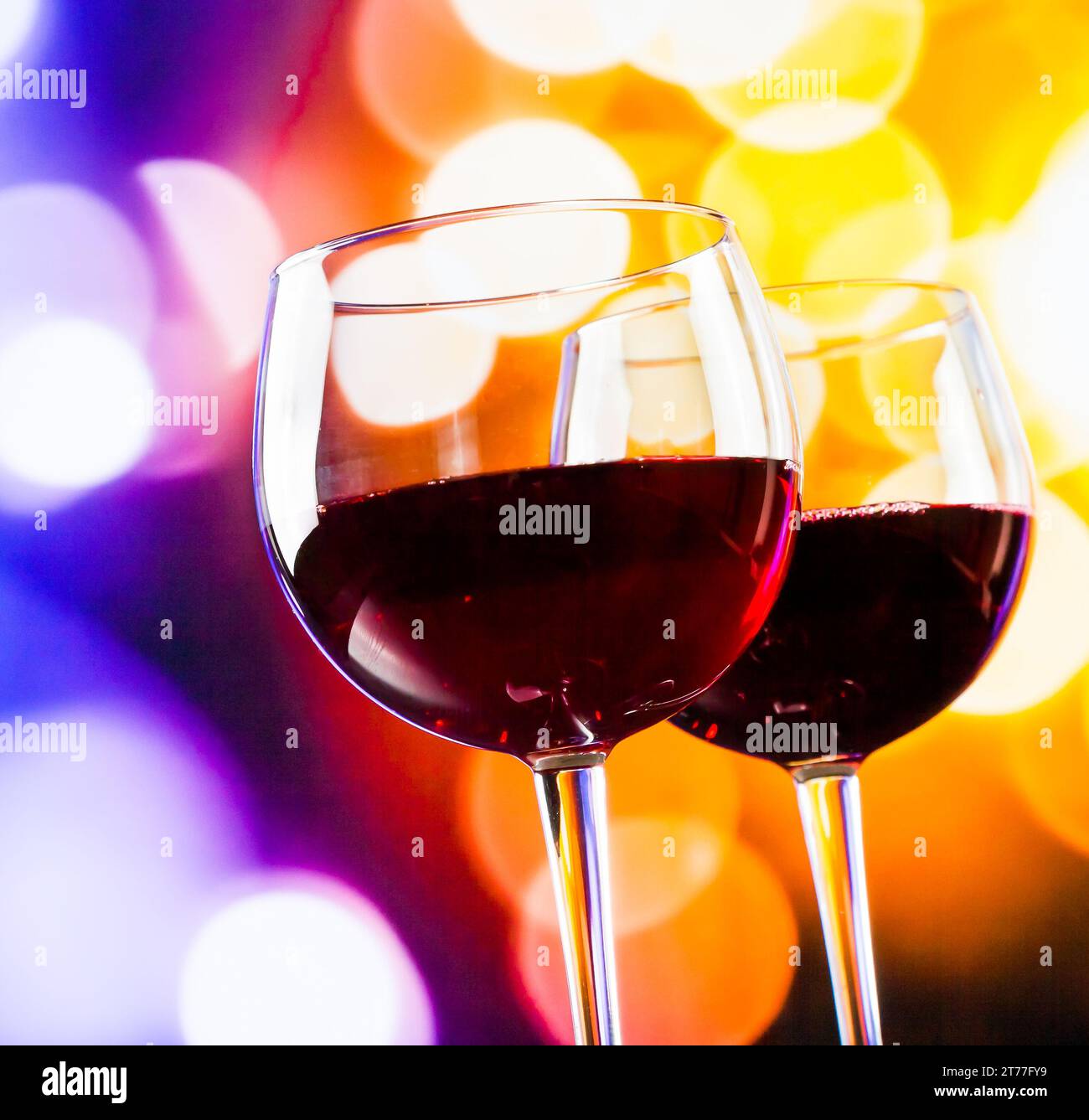 Zwei Rotweingläser vor farbenfrohen Bokeh-Lichtern, festliches und unterhaltsames Konzept Stockfoto