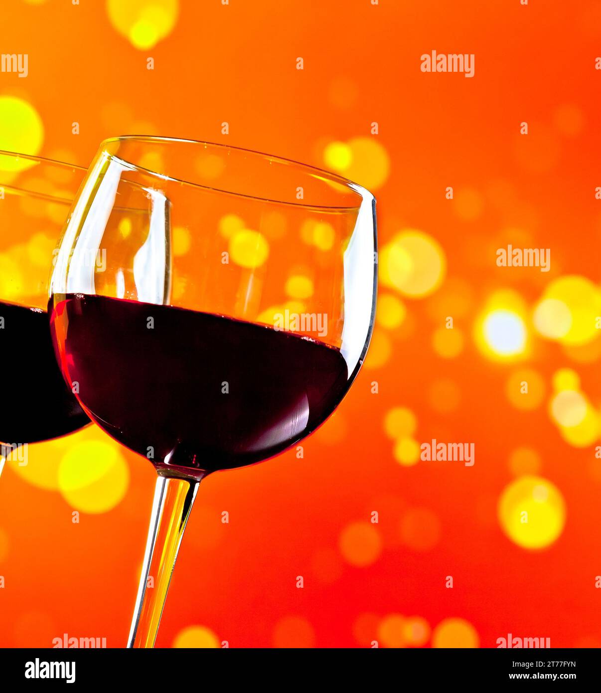 Zwei Rotweingläser vor goldenen Bokeh-Lichtern, festliches und unterhaltsames Konzept Stockfoto
