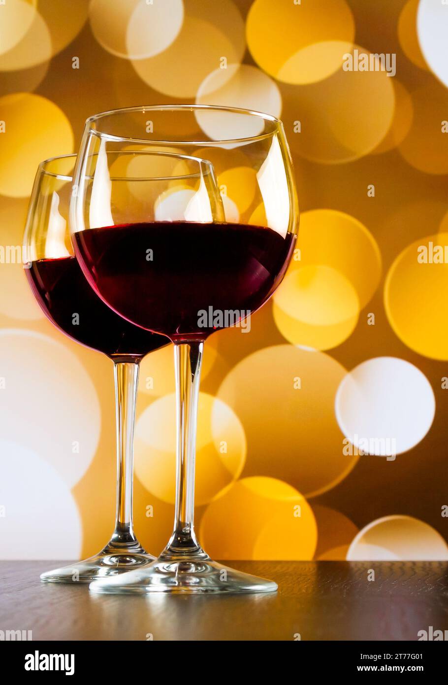 Rotweingläser auf Holztisch vor goldenem Bokeh-Hintergrund, festliches und unterhaltsames Konzept Stockfoto