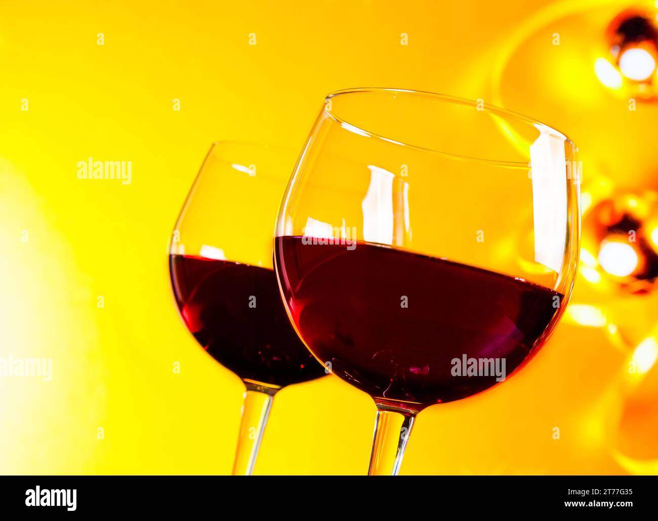 Zwei Rotweingläser vor goldenem Hintergrund, festliches und unterhaltsames Konzept Stockfoto