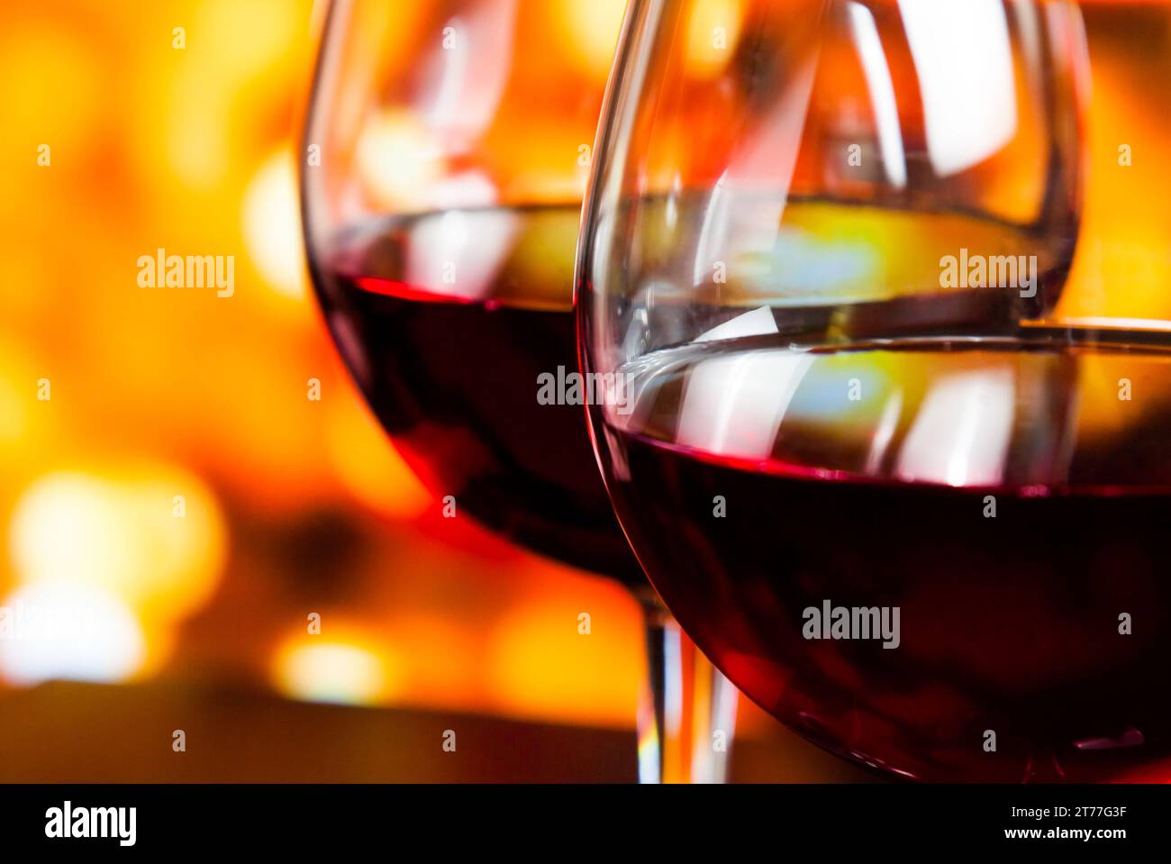 Detail von zwei Rotweingläsern vor farbenfrohen, unscharfen Lichtern im Hintergrund, festliches und unterhaltsames Konzept Stockfoto