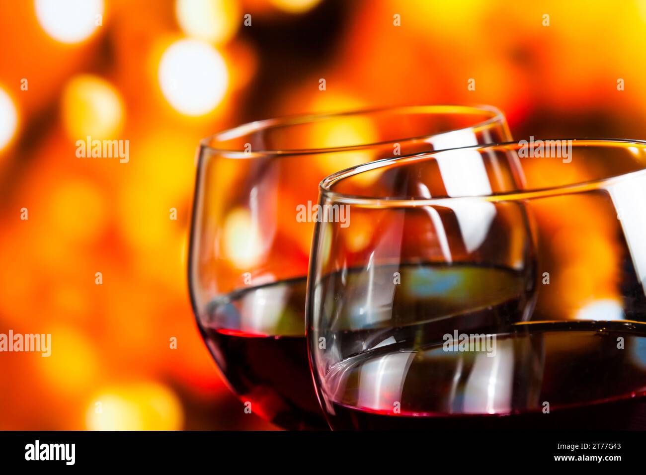 Zwei Rotweingläser vor farbenfrohen, unscharfen Lichtern im Hintergrund, festliches und unterhaltsames Konzept Stockfoto