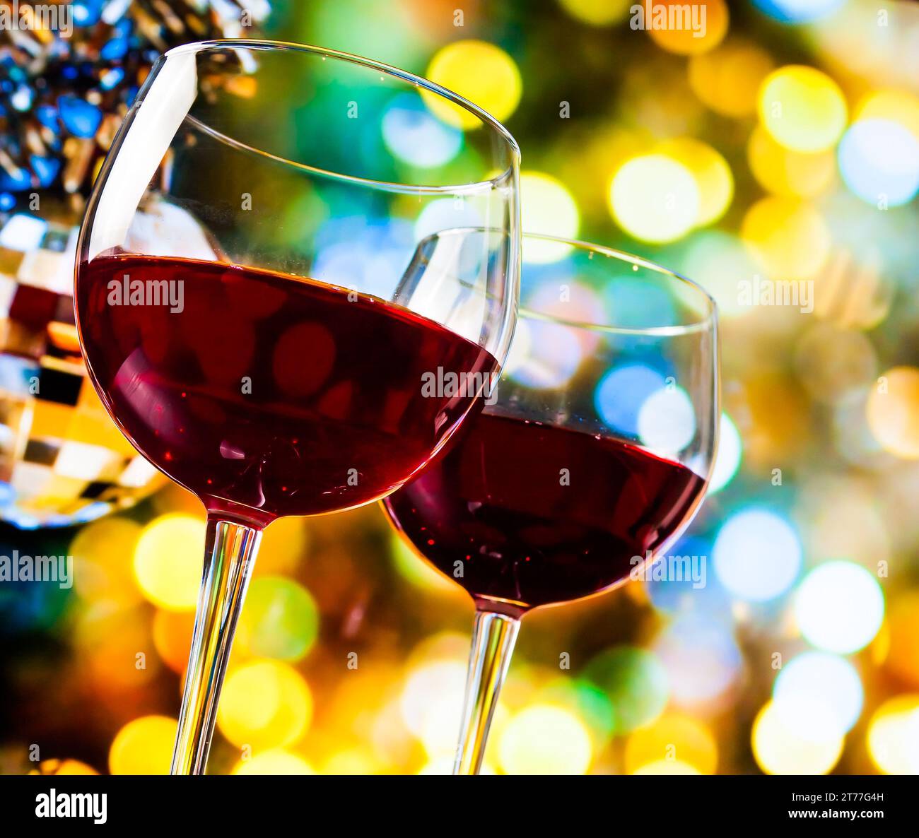 Rotweingläser vor bunten Bokeh-Lichtern und funkelndem Disco-Ball-Hintergrund, festliches und lustiges Konzept Stockfoto