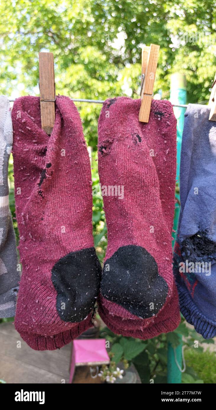 Sauber gewaschene alte, genähte, schäbige Socken hängen im Sommer draußen am Draht Stockfoto