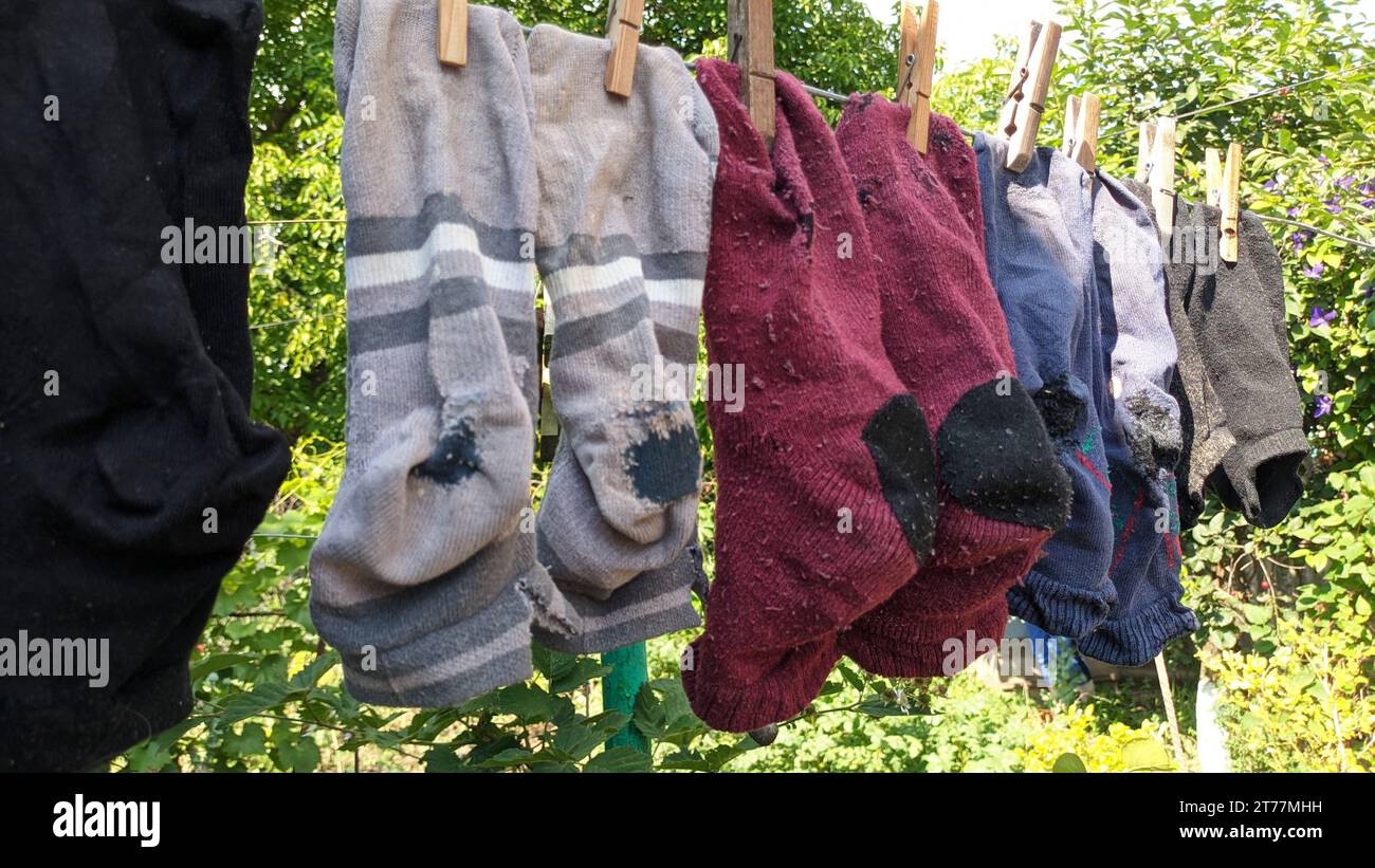 Sauber gewaschene alte, genähte, schäbige Socken hängen im Sommer draußen am Draht Stockfoto