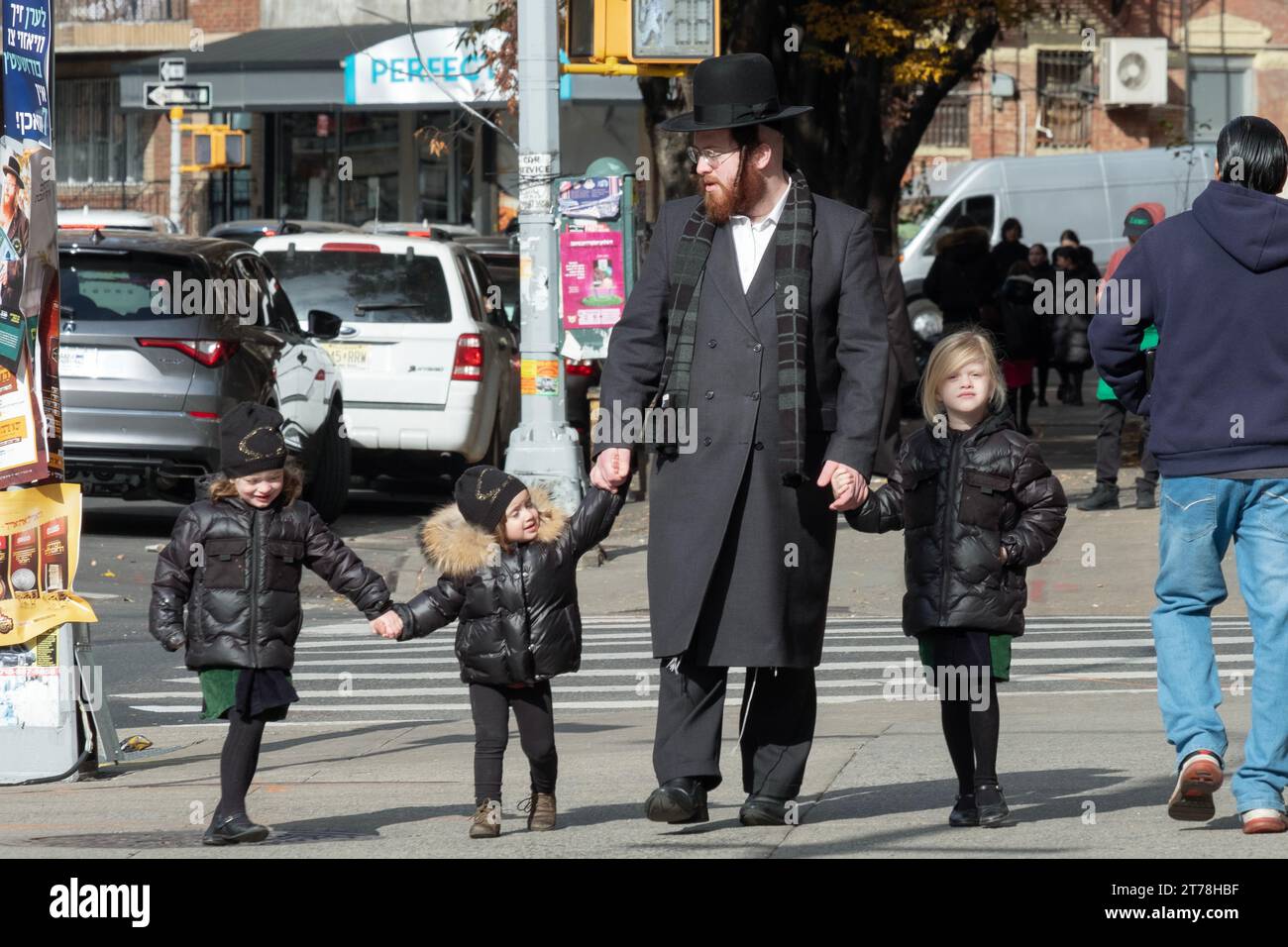 Ein chassidischer jüdischer Vater geht Hand in Hand mit seinem Sohn und zwei Töchtern. An der Bedford Avenue in Williamsburg, Brooklyn, New York. Stockfoto