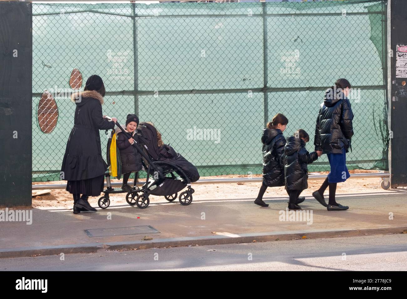 Eine ausgedehnte orthodoxe jüdische Familie spaziert an einem kühlen Herbsttag im Jahr 2023 an einer Baustelle vorbei. In Williamsburg, Brooklyn, New York City. Stockfoto