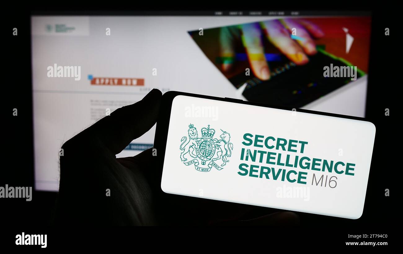 Person, die ein Smartphone mit dem Siegel des britischen Geheimdienstes Secret Intelligence Service (SIS, MI6) vor der Website hält. Schwerpunkt auf dem Display des Telefons. Stockfoto