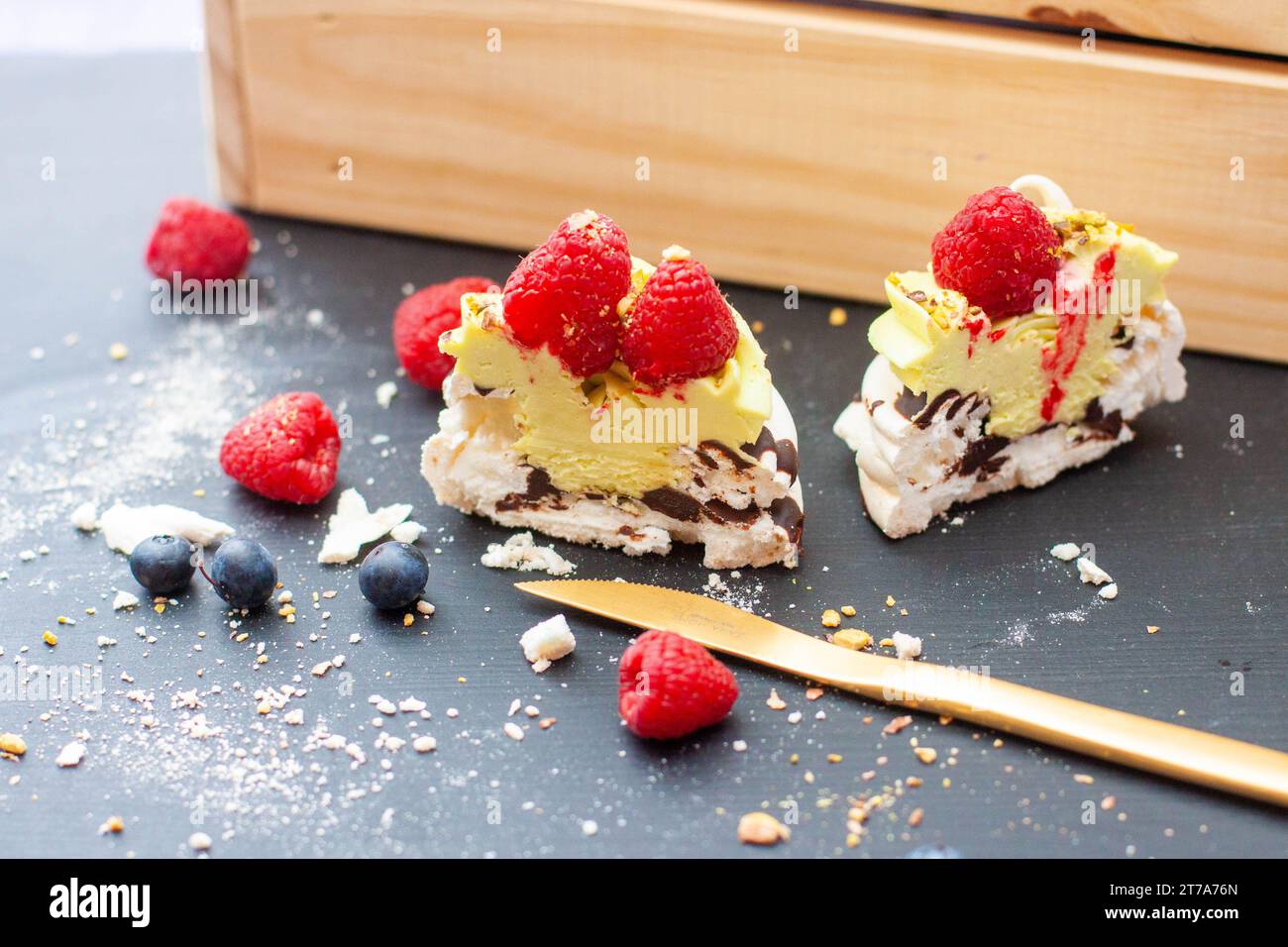 Nahaufnahme von Mini-pavlova-Kuchen mit Pistazien- und Schokoladenfüllung. Desserts mit Schlagsahne und frischer Himbeere Stockfoto