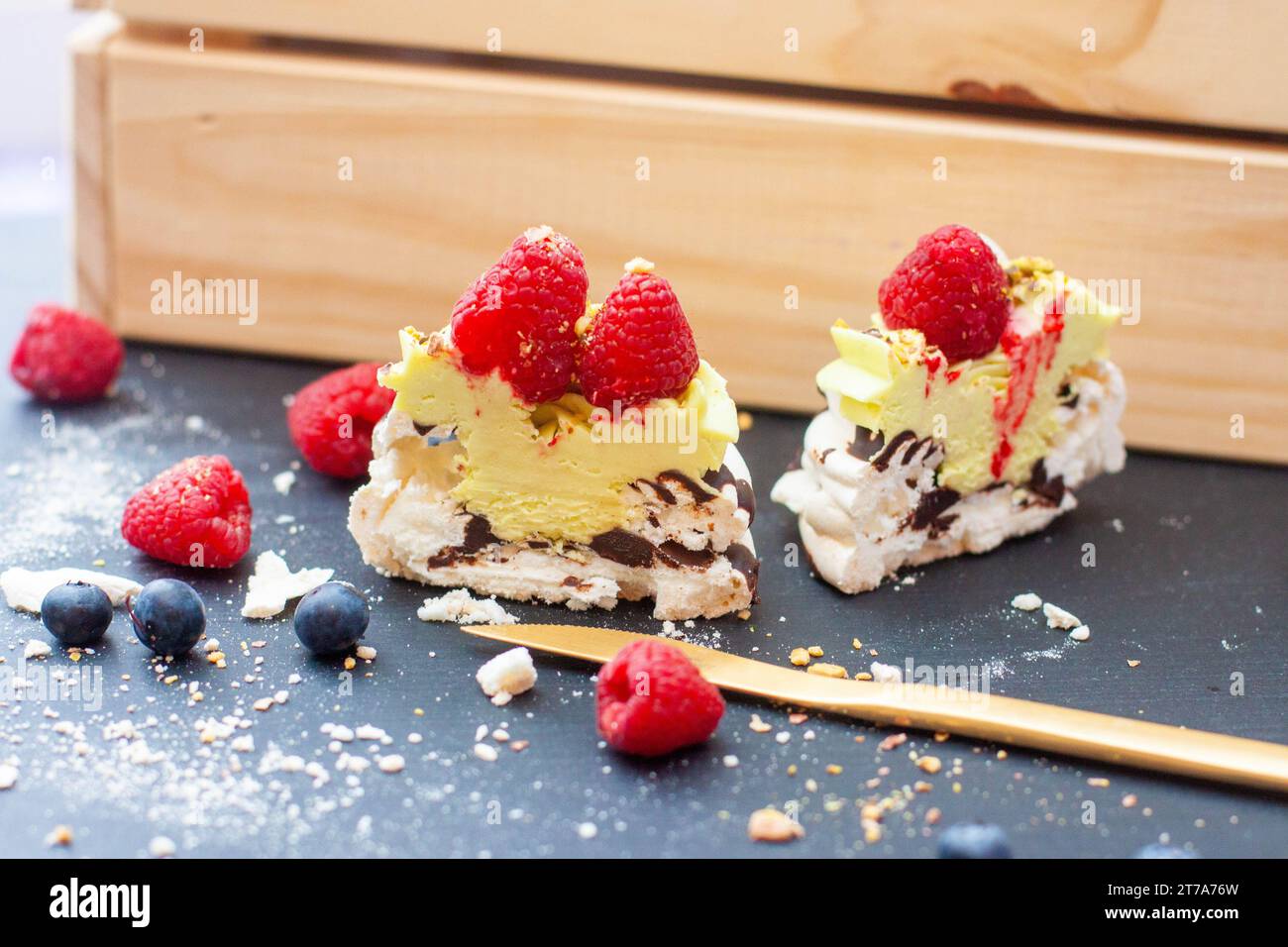 Nahaufnahme von Mini-pavlova-Kuchen mit Pistazien- und Schokoladenfüllung. Desserts mit Schlagsahne und frischer Himbeere Stockfoto