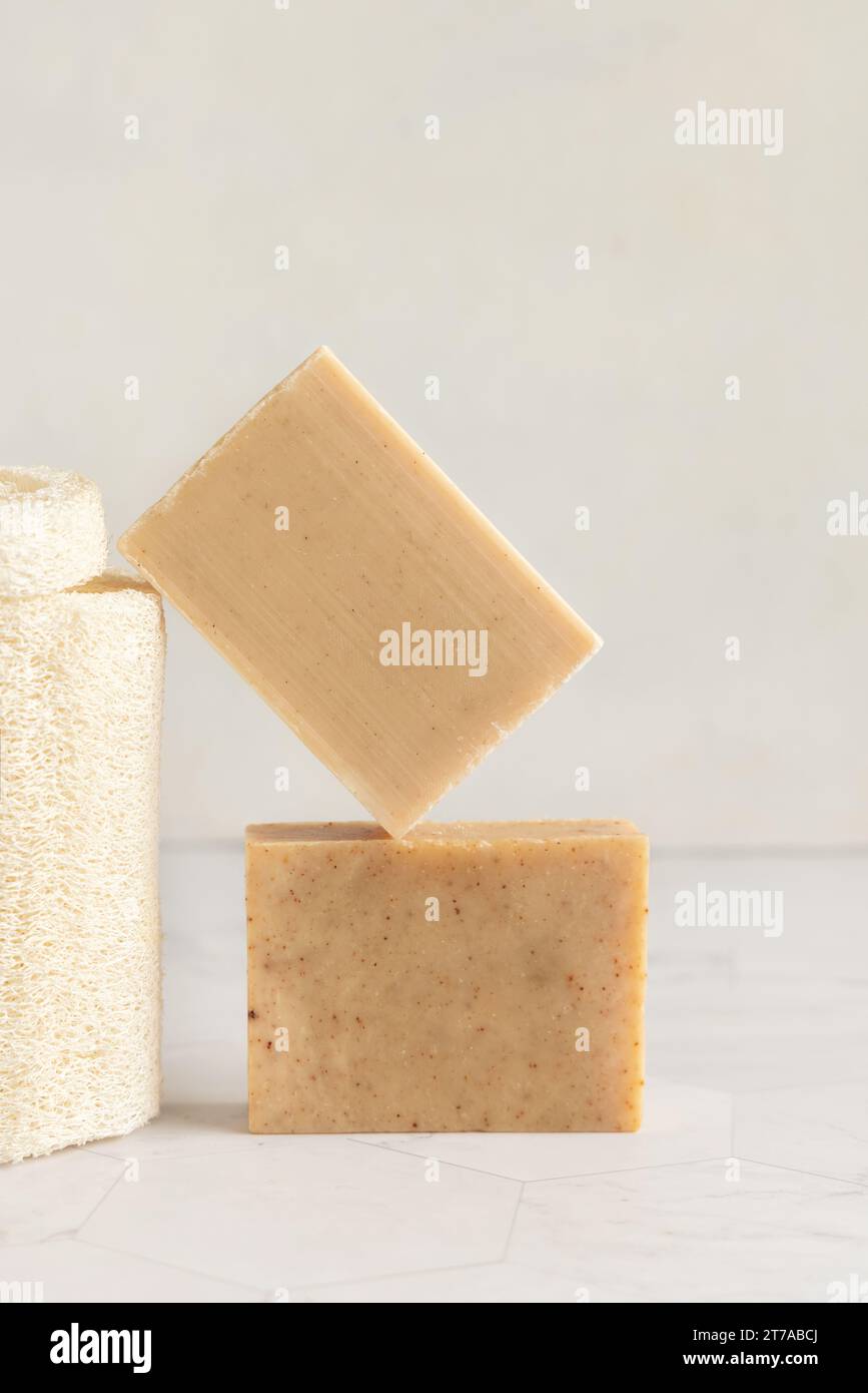 Beige handgemachte Seifenstangen auf Marmortisch in der Nähe des natürlichen Luffa Schwammes, Kopierraum. Natürliche pflanzliche Produkte für die Gesichts- und Körperhygiene Stockfoto
