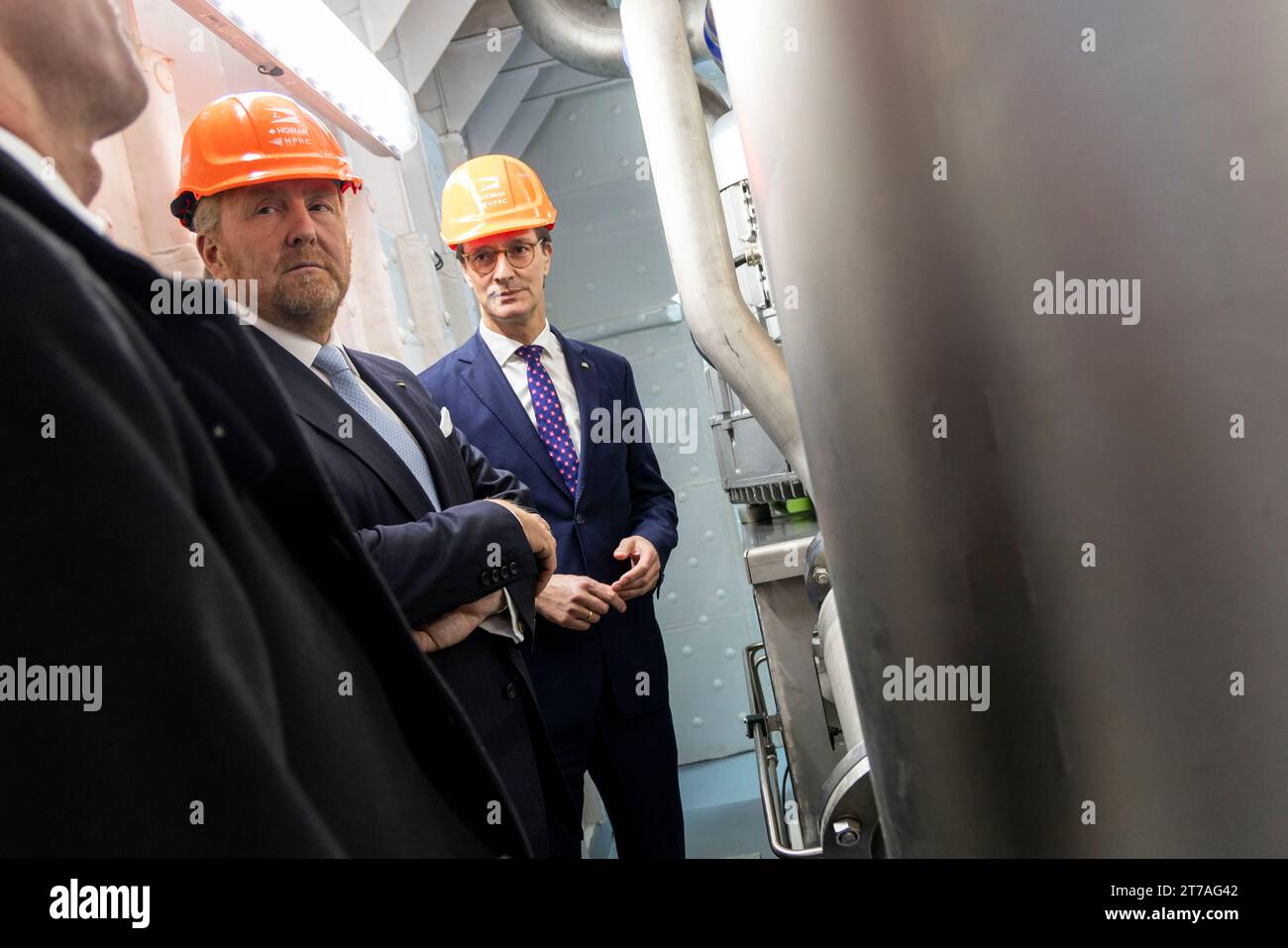 Duisburg, Deutschland. November 2023. Hendrik Wüst (CDU, r), Ministerpräsident von Nordrhein-Westfalen, und König Willem-Alexander von den Niederlanden (M) stehen im Maschinenraum eines Wasserstoffschiffes im Duisburger Hafen. Der niederländische König und der Ministerpräsident Nordrhein-Westfalens besuchen verschiedene Firmen und Einrichtungen. Quelle: Christoph Reichwein/dpa/Pool/dpa/Alamy Live News Stockfoto