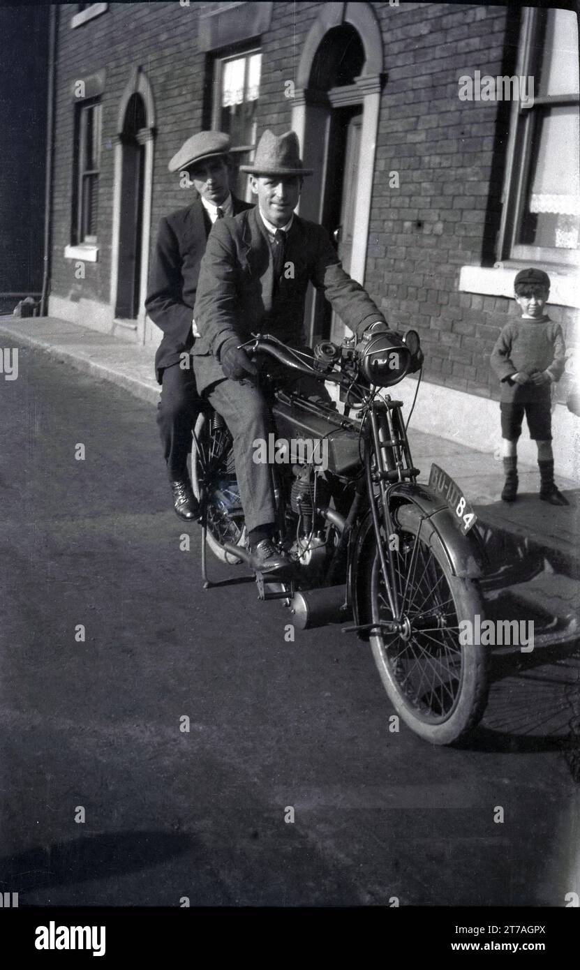 1950er Jahre, historisch, zwei gut gekleidete Gentleman, mit Hüten, auf einem alten Motorrad sitzend, ein Rudge Multi in einer Straße viktorianischer Reihenhäuser, Oldham, Manchester, England, Großbritannien. Der Rudge Multi wurde 1912 von der Rudge-Whitworth Cycle Company hergestellt und war ein riemengetriebenes Motorrad, das 1914 bei den berühmten TT-Rennen auf der Isle of man erfolgreich war, als Cyril Pullin die Tourist Trophy auf einem Rudge Multigear gewann. Stockfoto