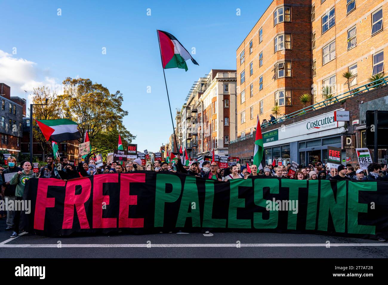 Die Menschen marschieren durch London mit Einem Banner für das freie Palästina, das zu Einer Waffenruhe im Gazastreifen während des Marsch für Palästina-Events in London, Großbritannien, aufruft Stockfoto